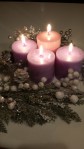 four lit candles. three purple, one pink